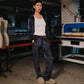 Person wearing a dark jacket and pants in an industrial setting