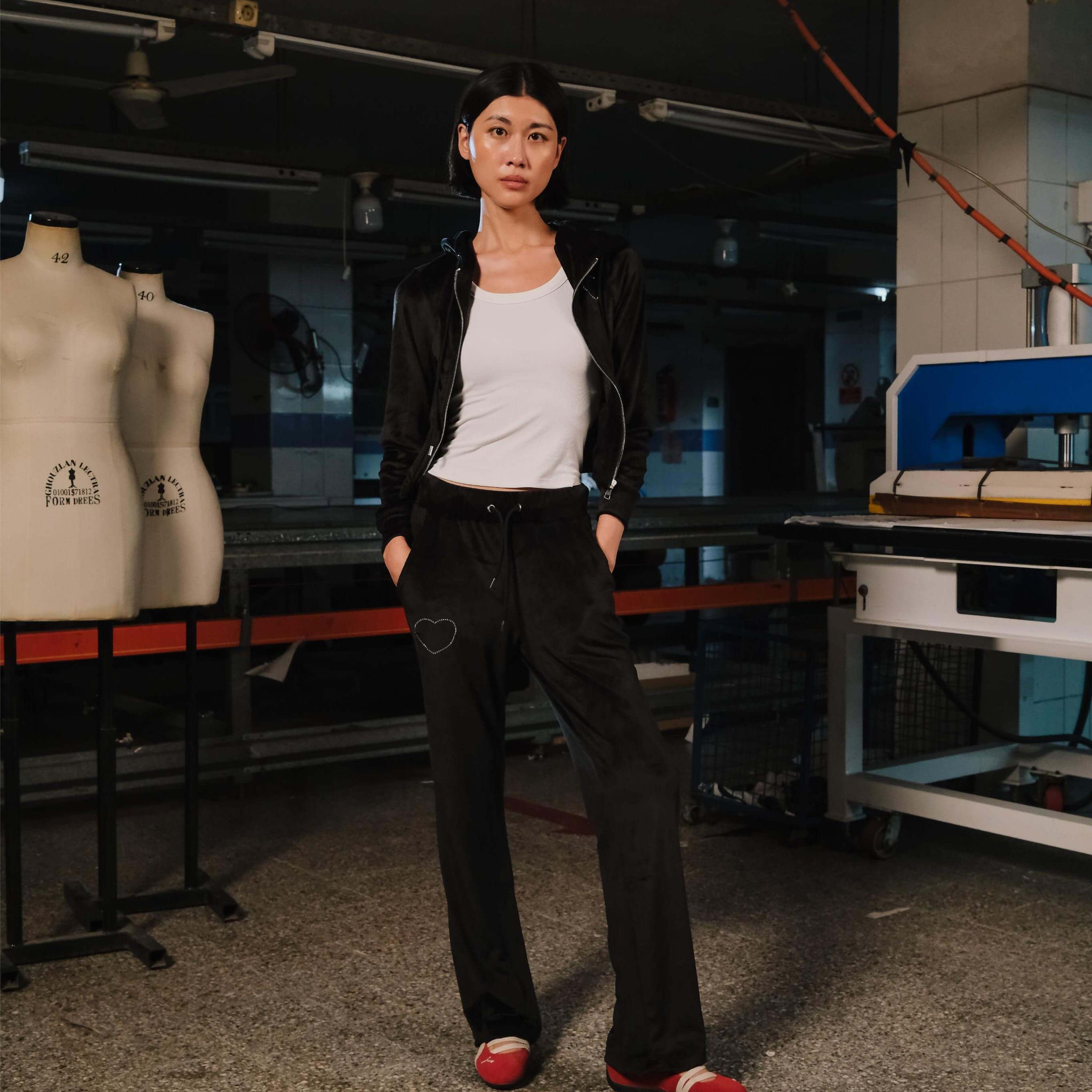 Person standing in a workshop with sewing machines and mannequins in the background