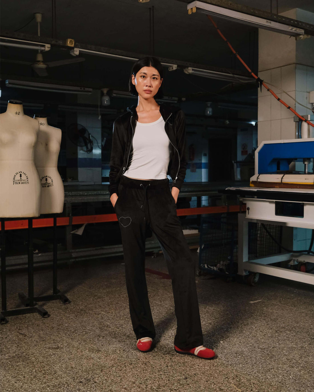Person standing in a workshop with sewing machines and mannequins in the background