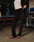 Person wearing black pants and red shoes in a workshop setting