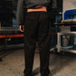 Person wearing black pants and a gray sweatshirt in an industrial setting