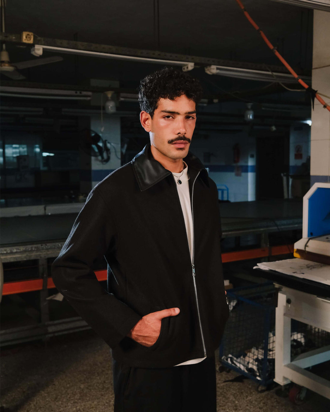 Man wearing a black jacket and white shirt in an industrial setting