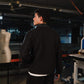 Person wearing a black jacket in an indoor setting with equipment and a mannequin.