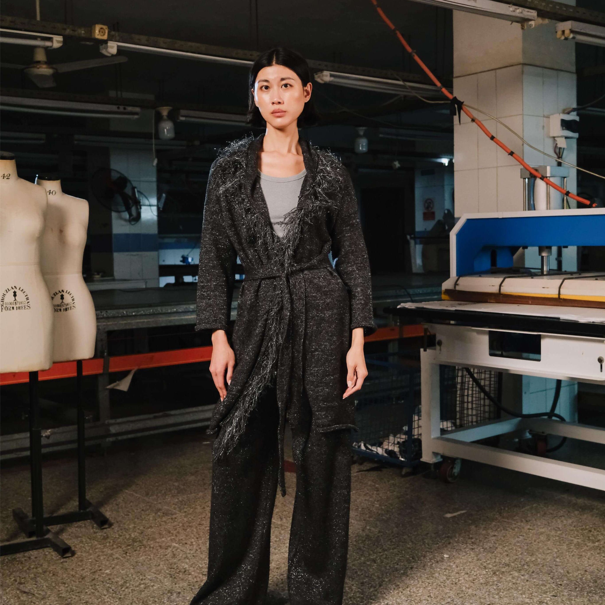 Person wearing a dark textured outfit in a workshop setting