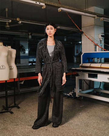 Person wearing a dark textured outfit in a workshop setting