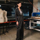 Person standing in a workshop or studio with sewing equipment and mannequins.