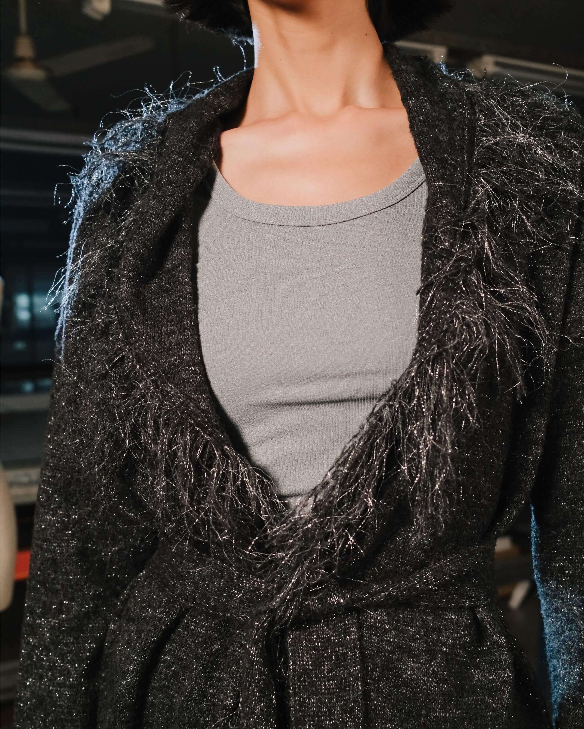 Person wearing a dark gray textured cardigan over a gray shirt.