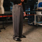 Person wearing gray pants and black shoes in an indoor setting with a mannequin and equipment in the background.