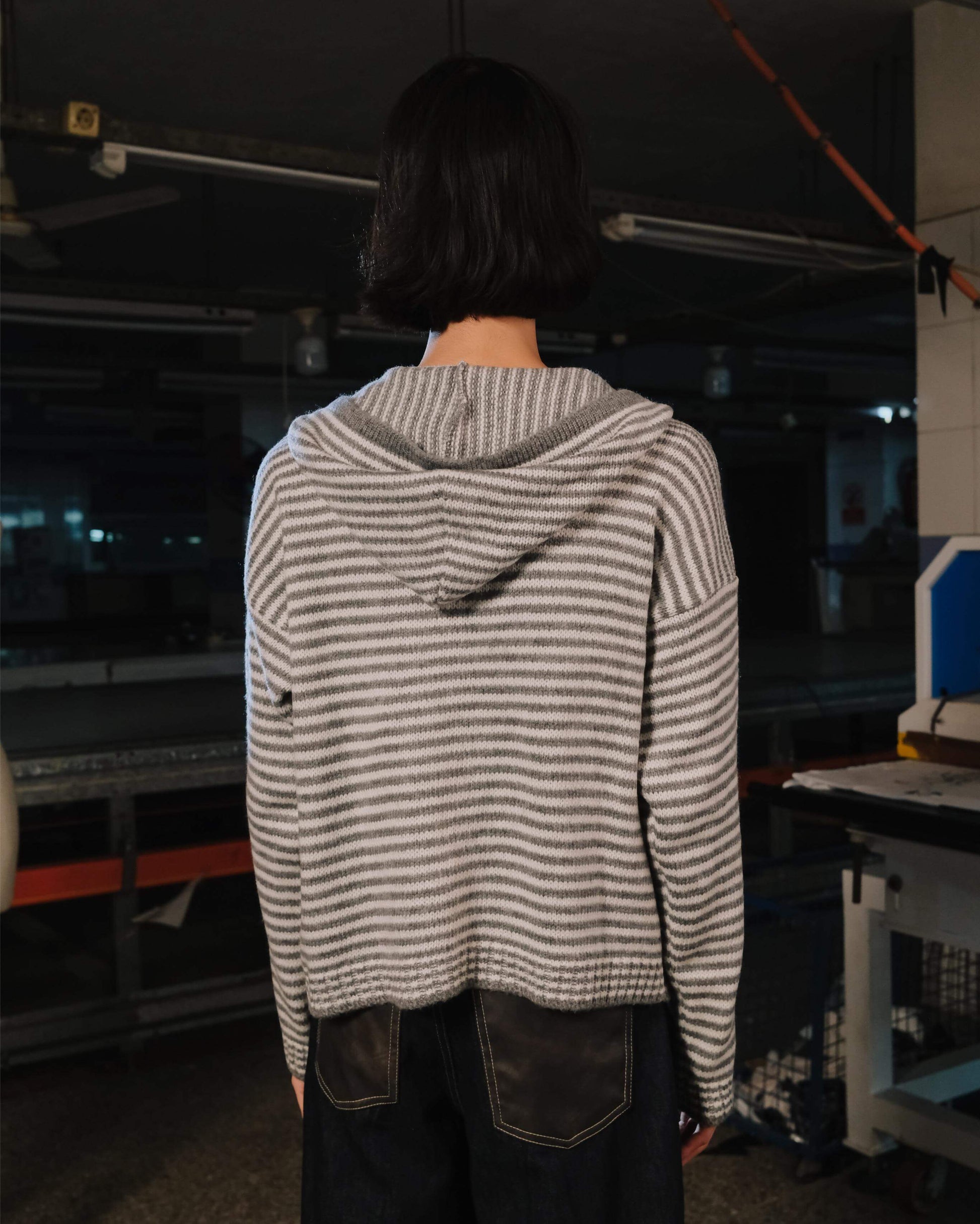 Person wearing a striped hoodie in an industrial setting