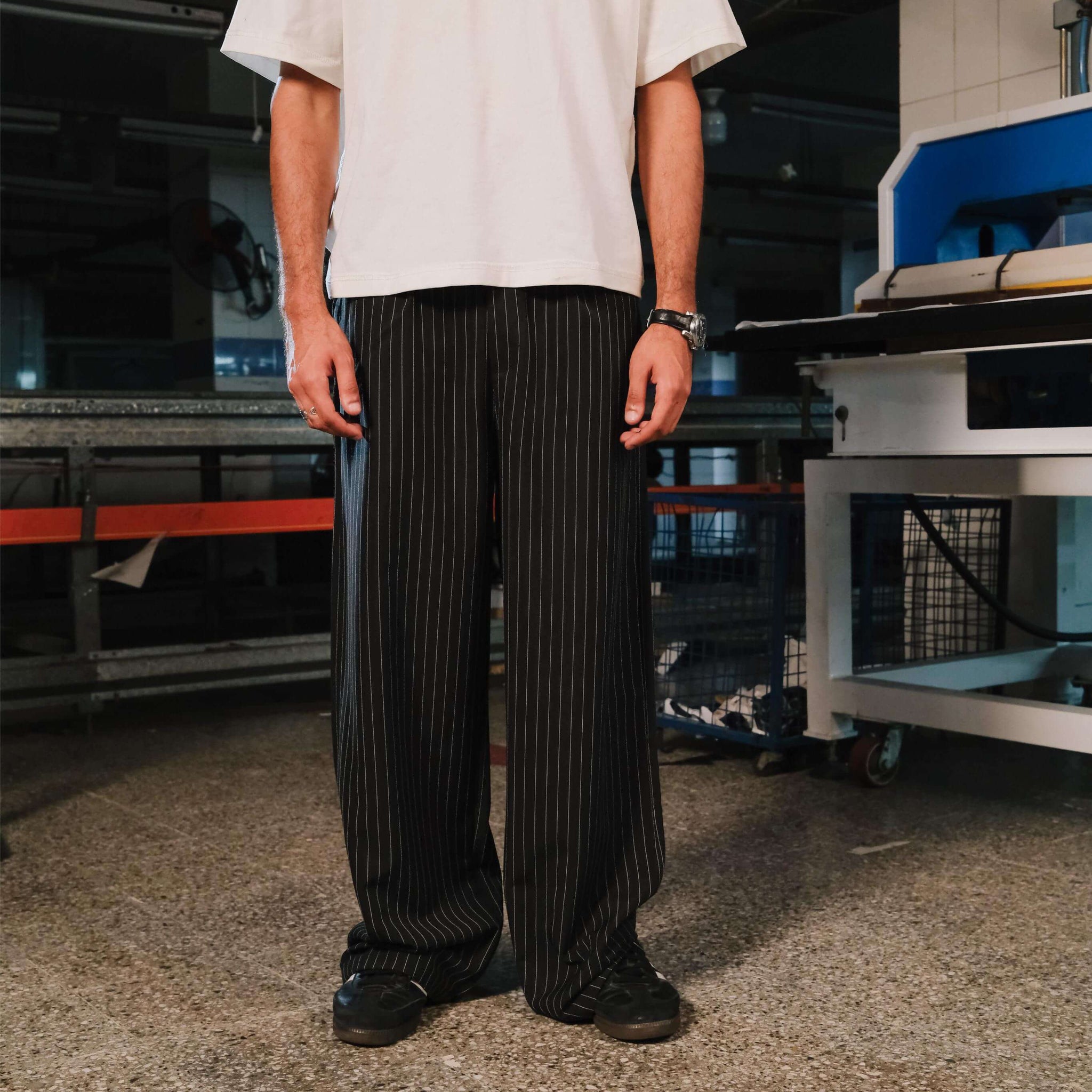 Person wearing a white shirt and black pinstripe pants in an industrial setting