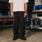 Person wearing a white shirt and black pinstripe pants in an industrial setting