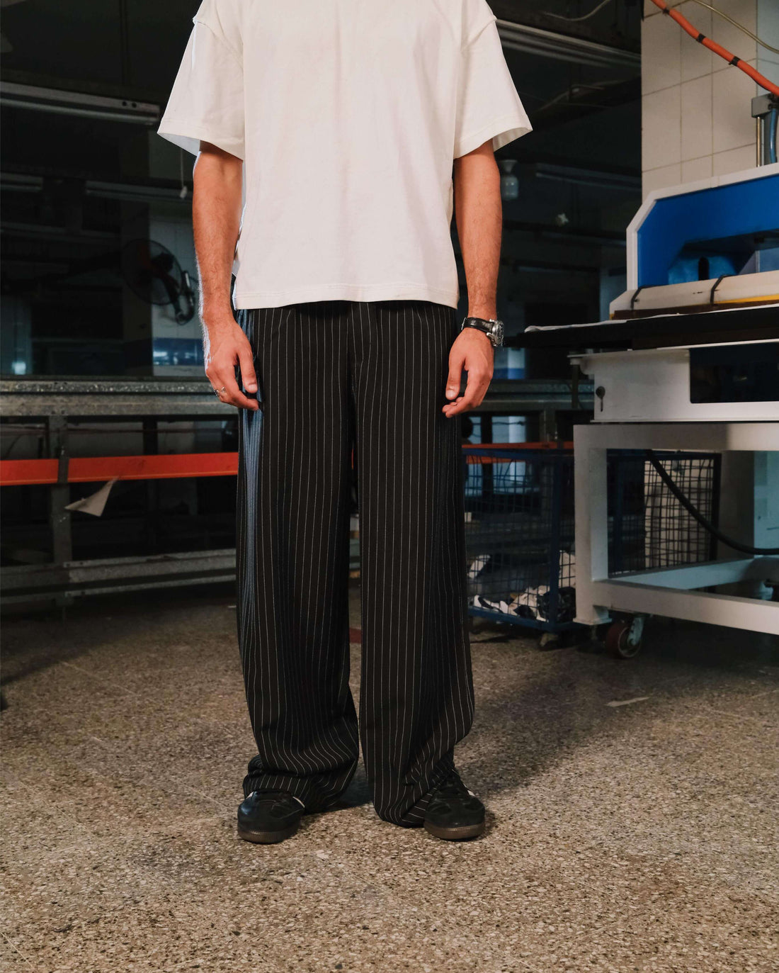 Person wearing a white shirt and black pinstripe pants in an industrial setting