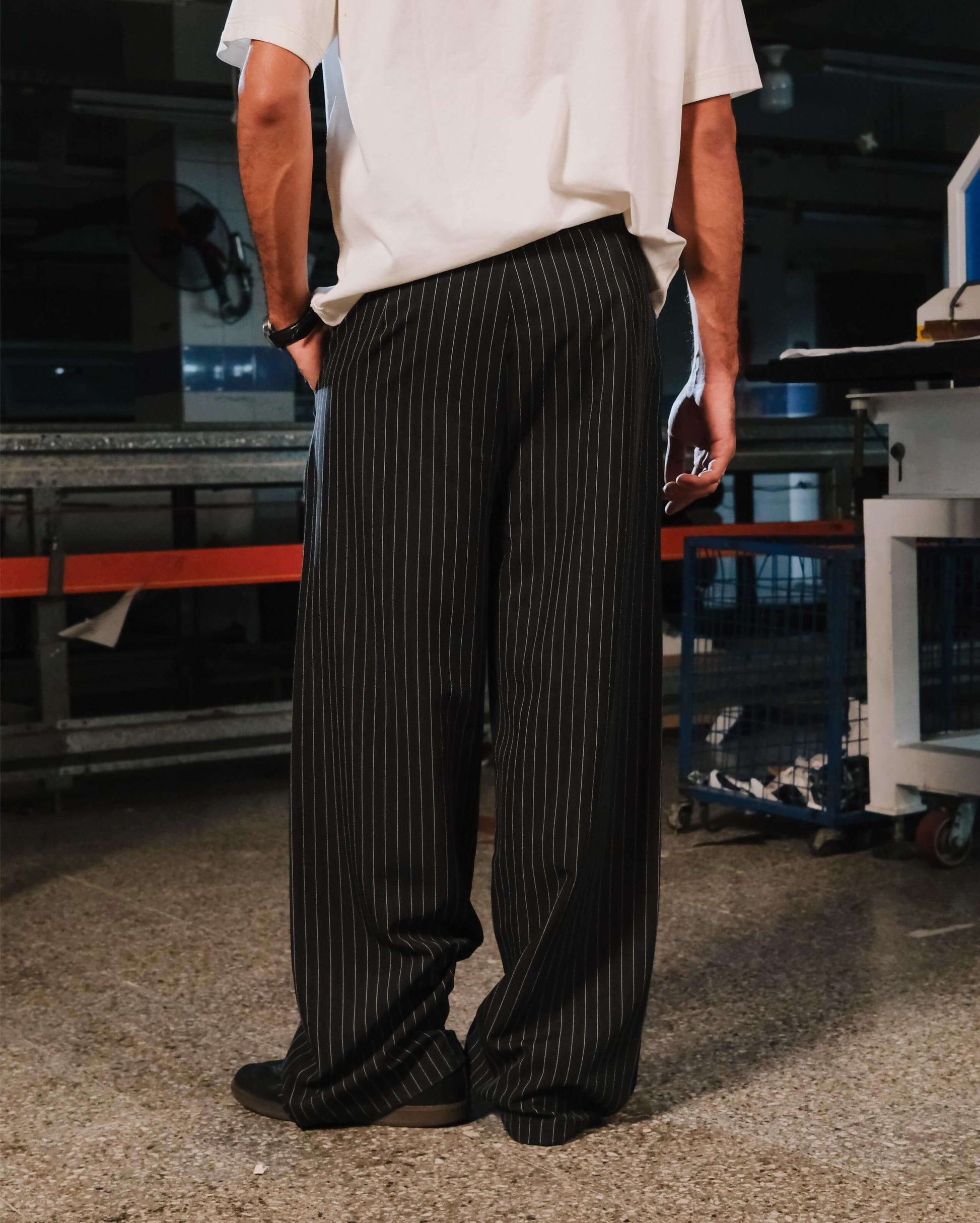 Person wearing a white shirt and black pinstripe pants in an industrial setting