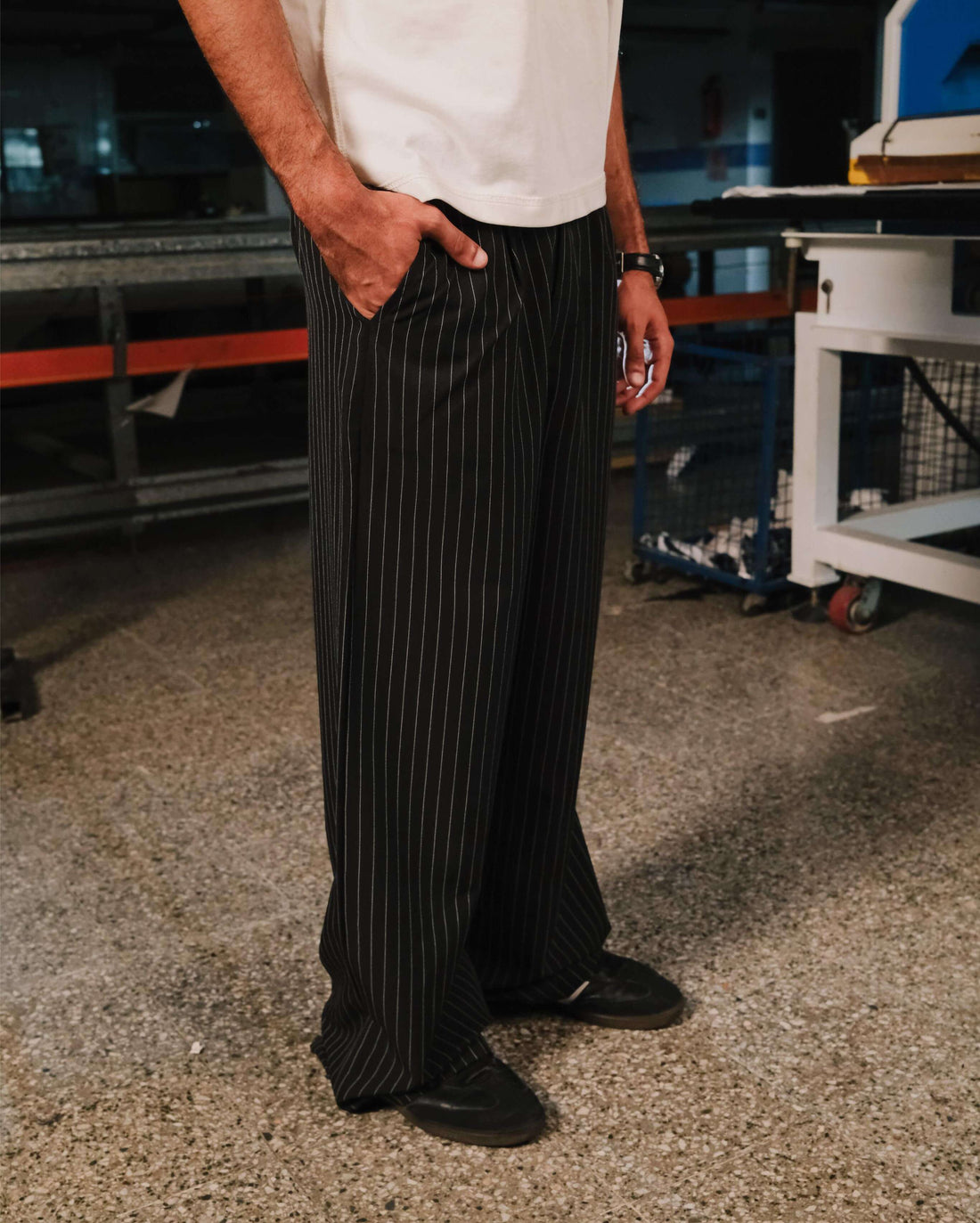 Person wearing a white shirt and black pinstripe pants in an industrial setting