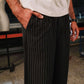 Person wearing black pinstripe pants and a white shirt in an indoor setting.