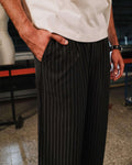 Person wearing black pinstripe pants and a white shirt in an indoor setting.