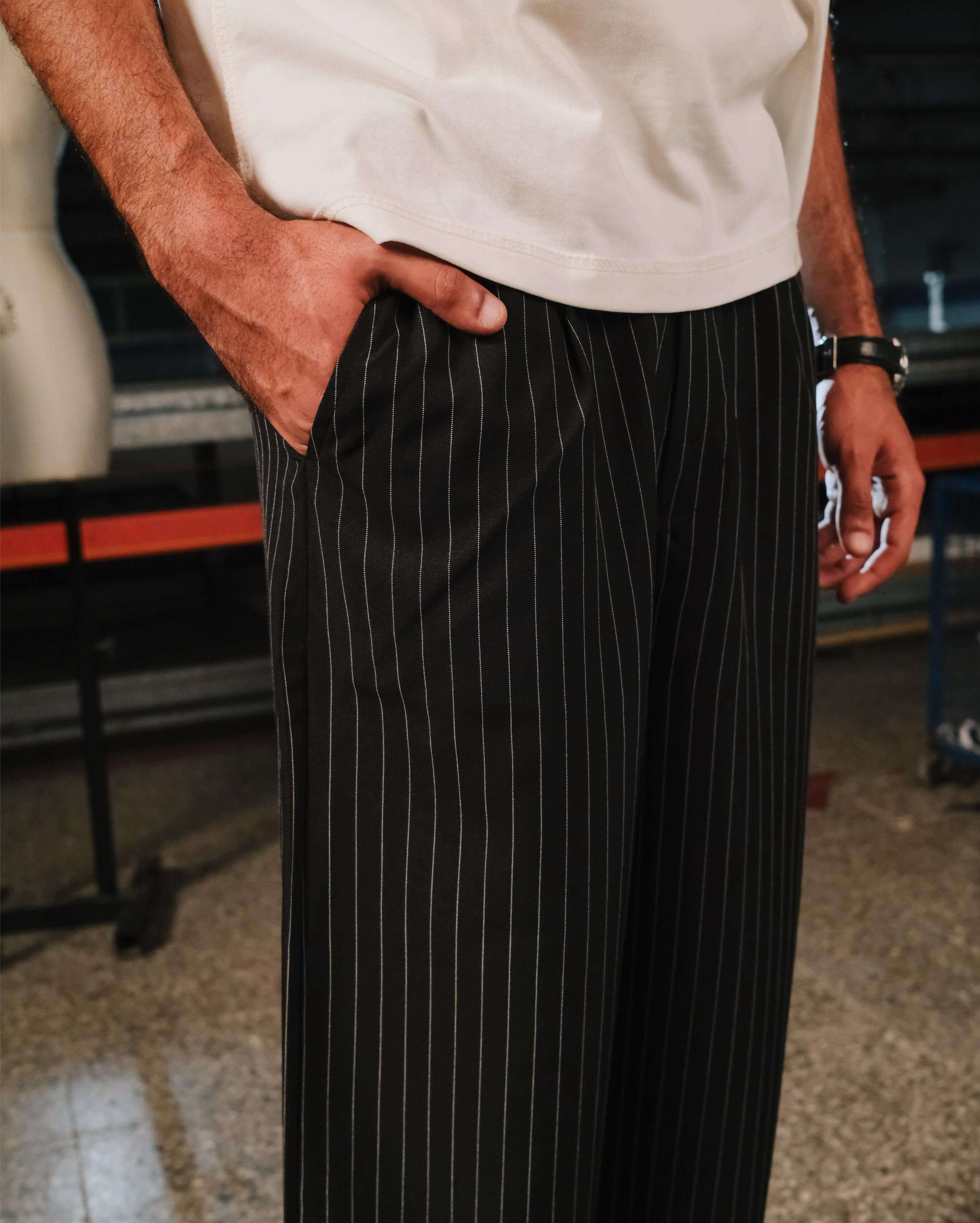 Person wearing black pinstripe pants and a white shirt in an indoor setting.