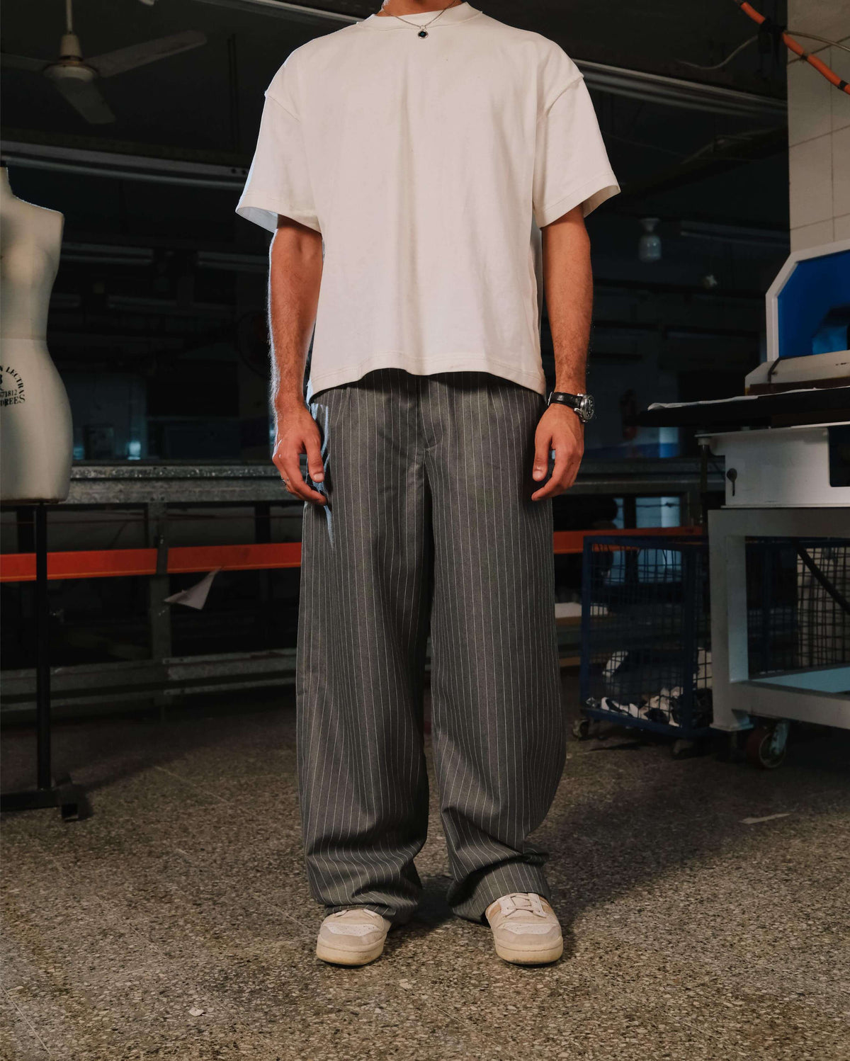 Person wearing a white shirt and gray striped pants in an industrial setting