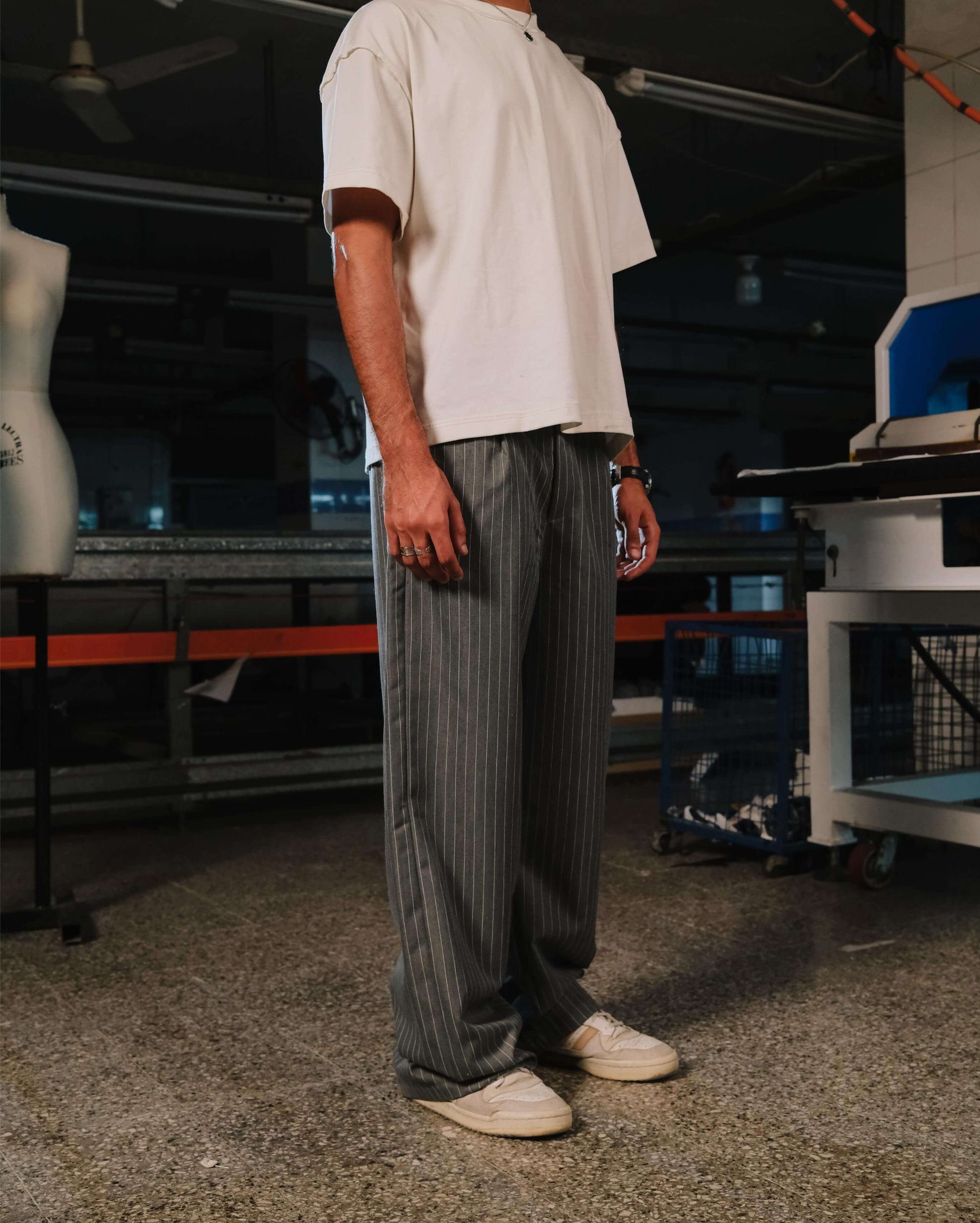 Person wearing a white t-shirt and gray striped pants in an indoor setting