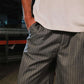 Person wearing a beige shirt and gray pinstripe pants with a blurred background