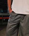 Person wearing a beige shirt and gray pinstripe pants with a blurred background