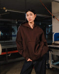 Person wearing a brown hoodie in an industrial setting