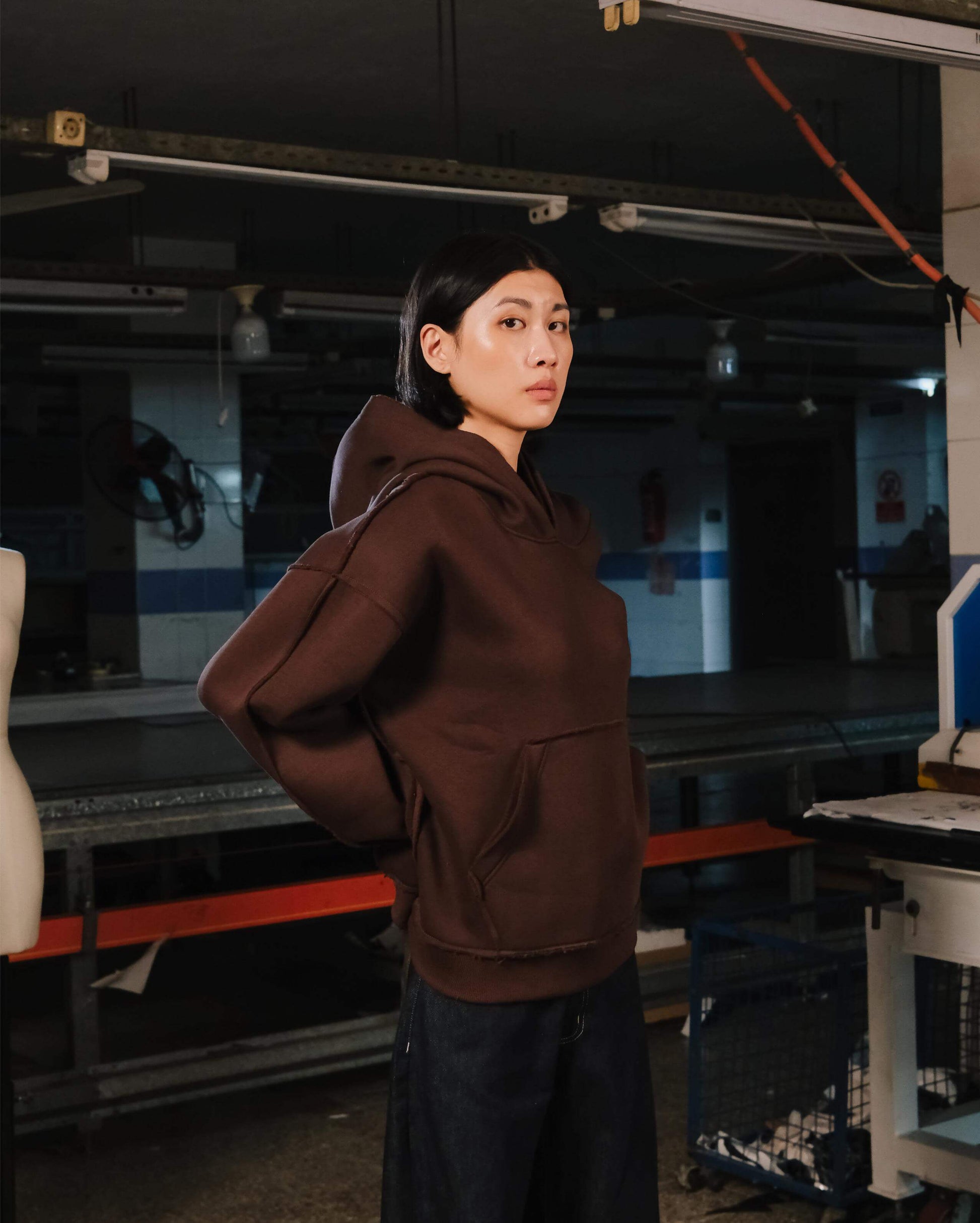 Person wearing a brown hoodie in an industrial setting