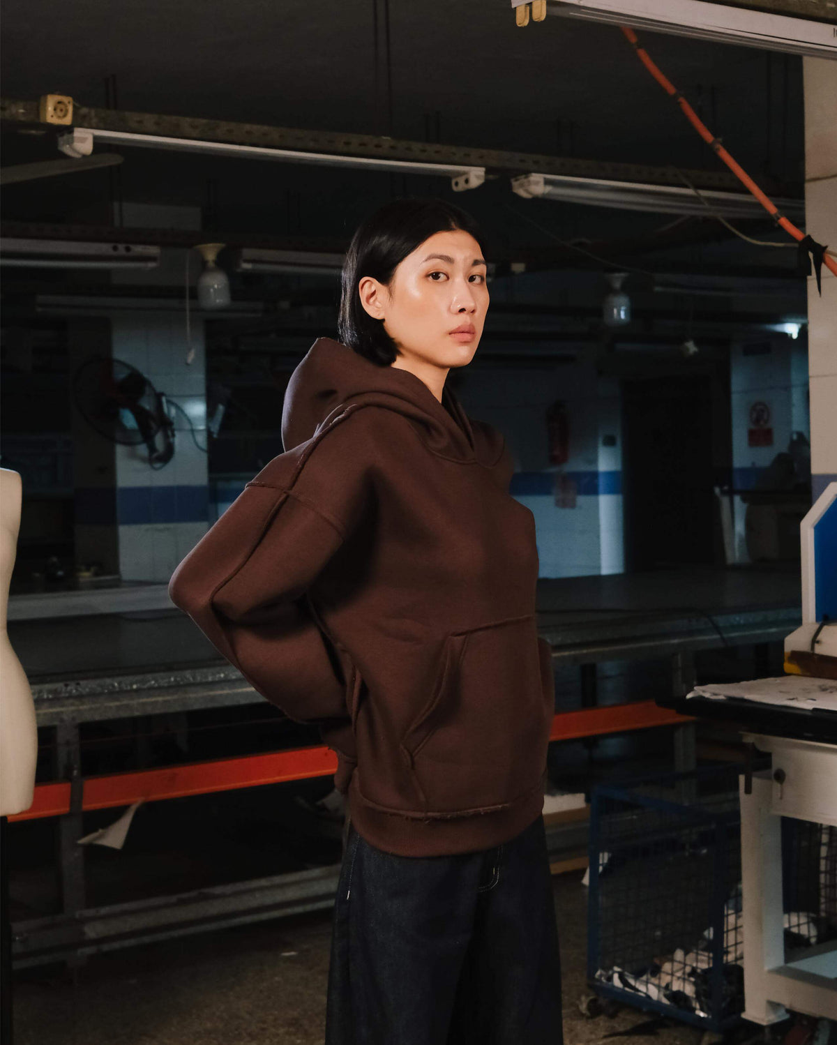 Person wearing a brown hoodie in an industrial setting