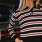 Person wearing a black, white, and red striped shirt with a blurred background