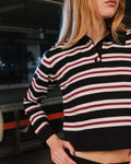 Person wearing a black, white, and red striped shirt with a blurred background