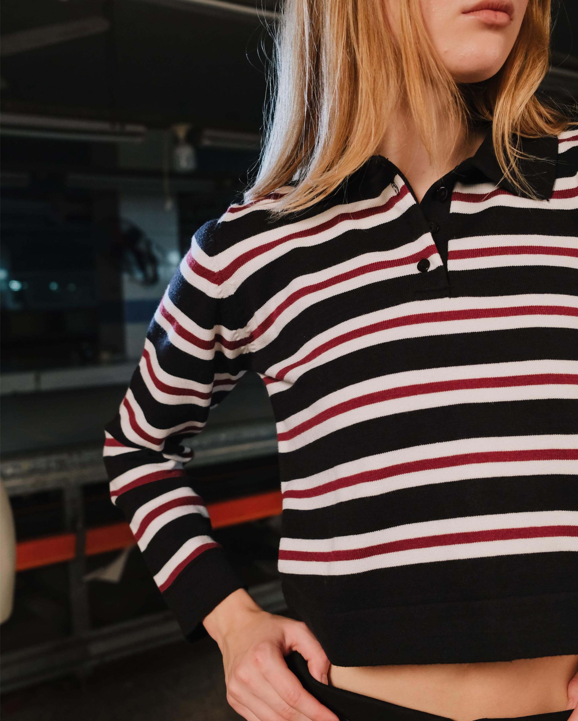 Person wearing a black, white, and red striped shirt with a blurred background