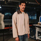 Man wearing a beige jacket with a brown collar in an industrial setting