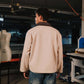 Person wearing a beige jacket in a workshop setting