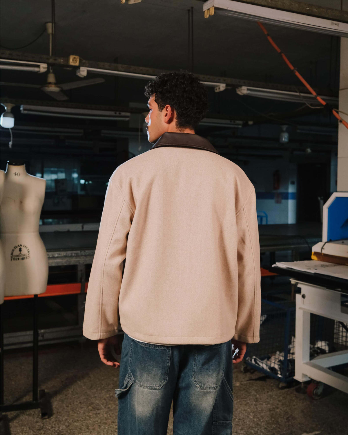 Person wearing a beige jacket in a workshop setting