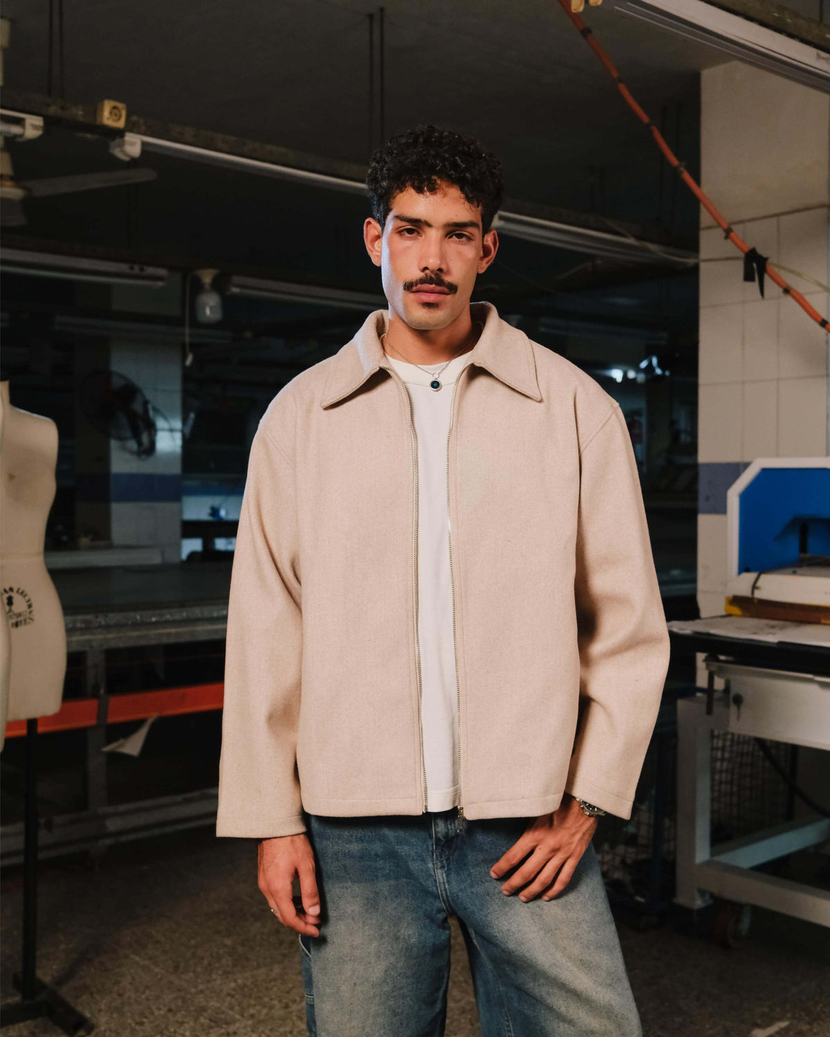 Man wearing a beige jacket and white shirt in a workshop setting