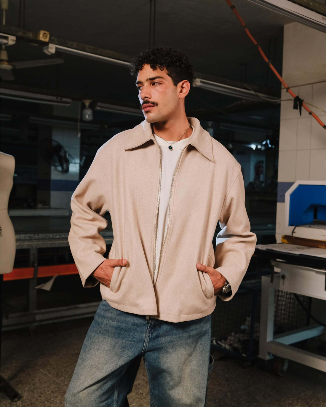Man wearing a beige jacket and white shirt in a workshop setting