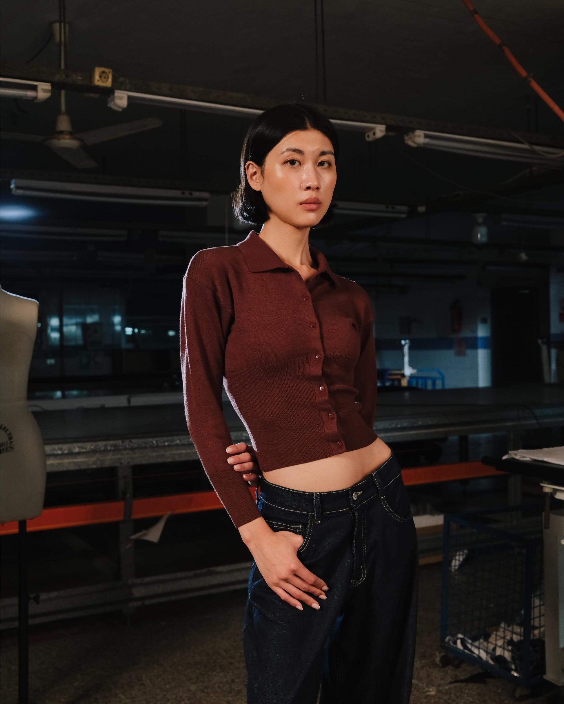Person wearing a maroon shirt and dark pants in an industrial setting
