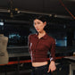 Person wearing a maroon shirt in an indoor setting with equipment and tools.