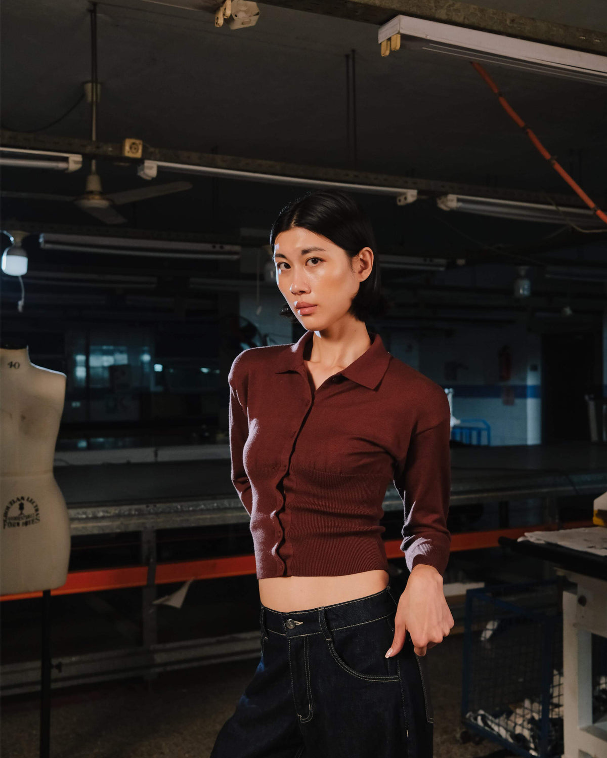 Person wearing a maroon shirt in an indoor setting with equipment and tools.