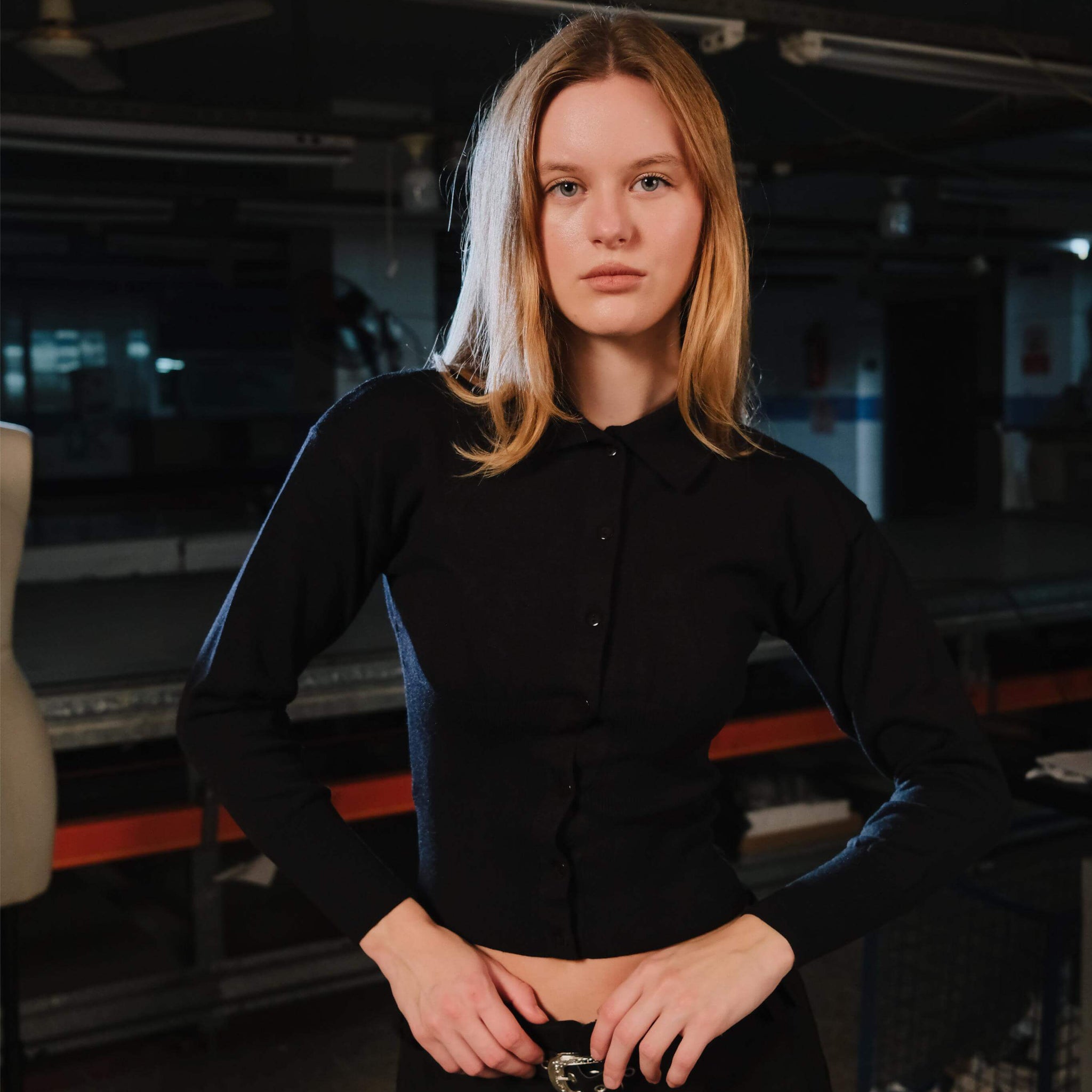 Person wearing a black outfit in an indoor setting with equipment in the background