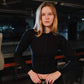Person wearing a black outfit in an indoor setting with equipment in the background