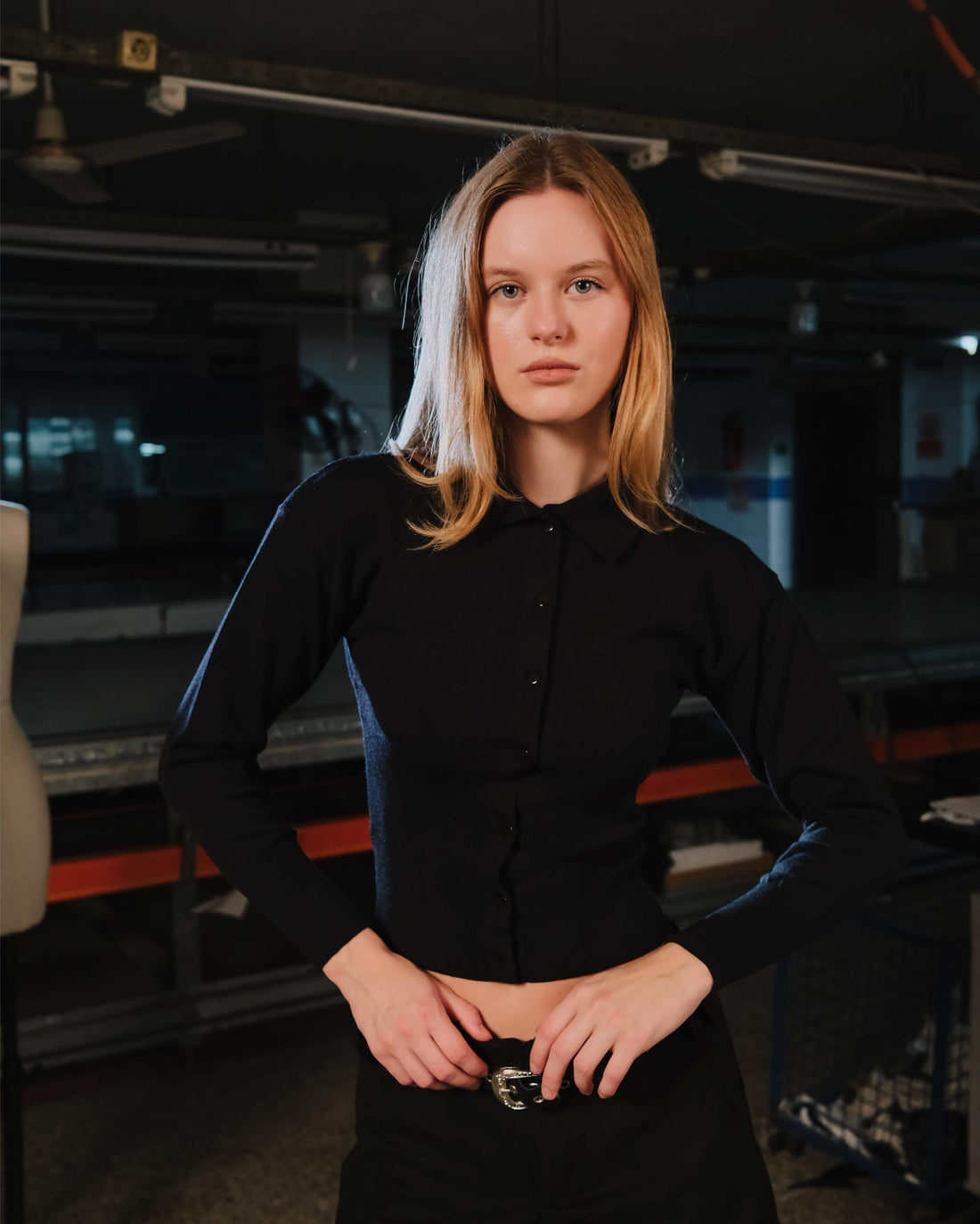 Person wearing a black outfit in an indoor setting with equipment in the background