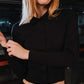 Person wearing a black long-sleeve crop top in an indoor setting