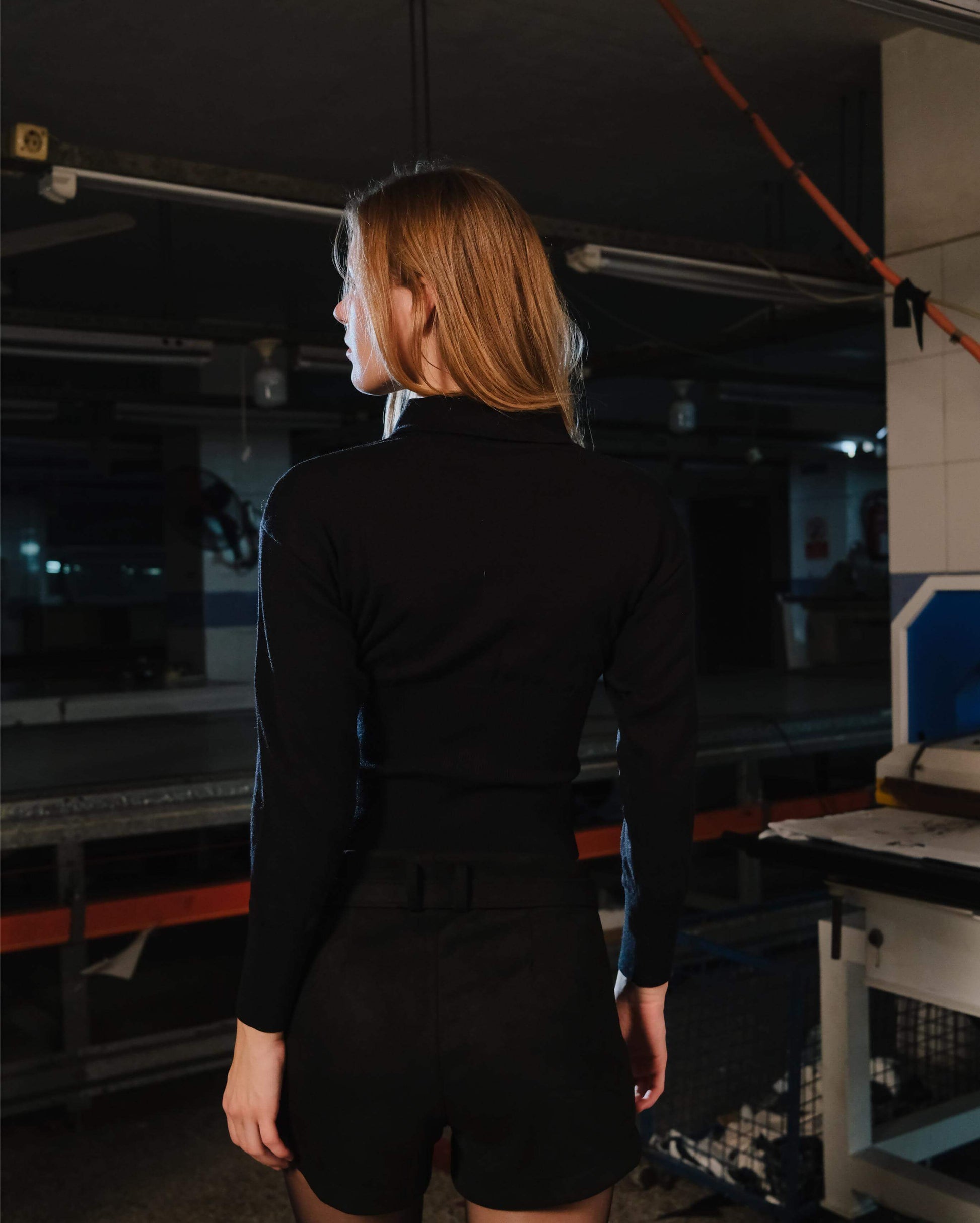 Person wearing a black outfit in an industrial setting