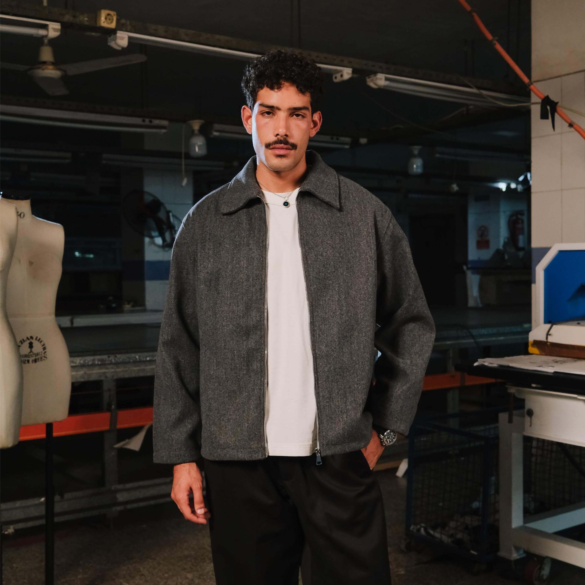 Man wearing a gray jacket over a white shirt in an industrial setting