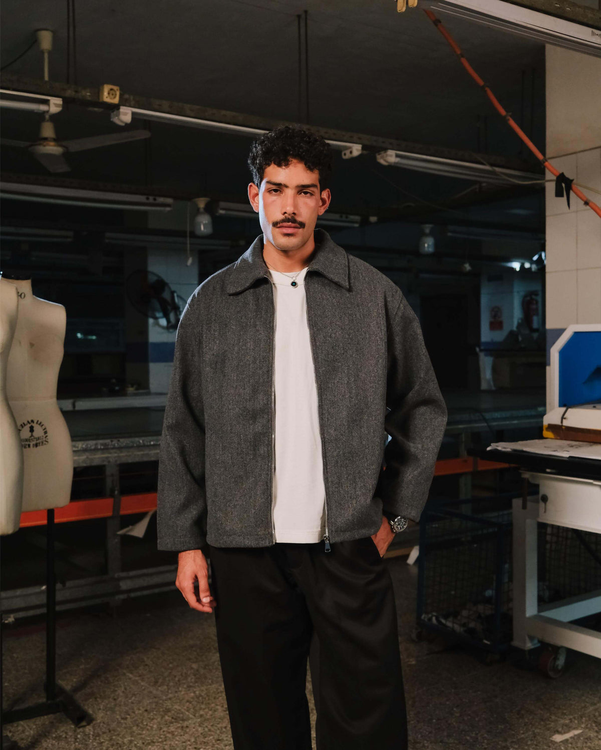Man wearing a gray jacket over a white shirt in an industrial setting