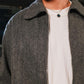 Person wearing a gray coat over a white shirt with a blurred background