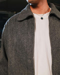 Person wearing a gray coat over a white shirt with a blurred background
