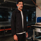 Man wearing a black jacket and white shirt in an industrial setting