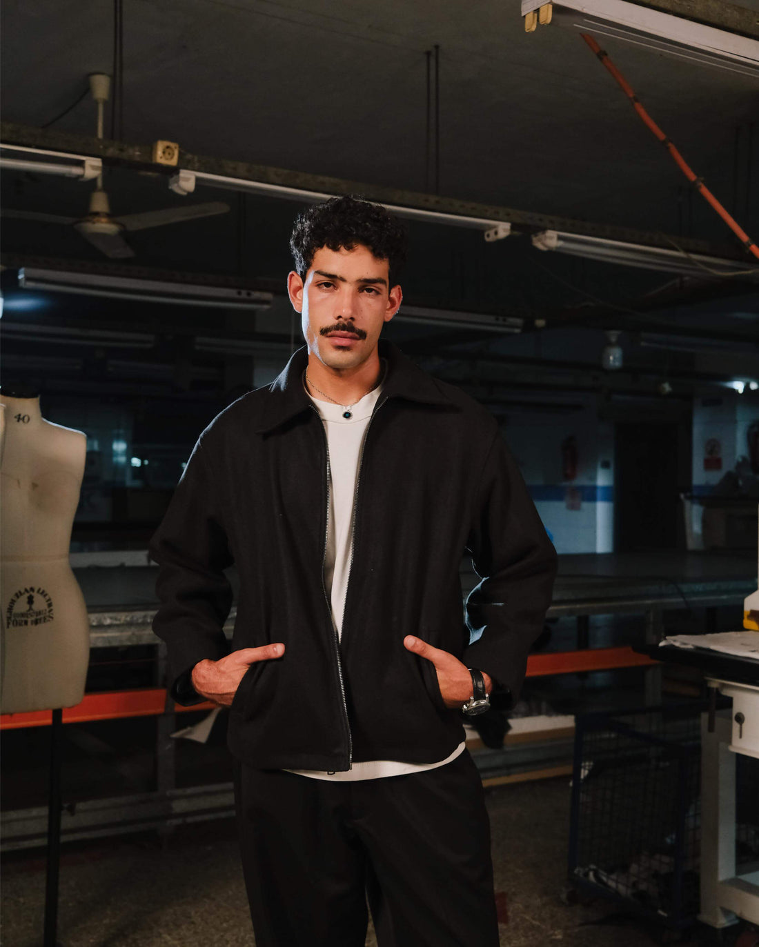Man wearing a black jacket and white shirt in an industrial setting